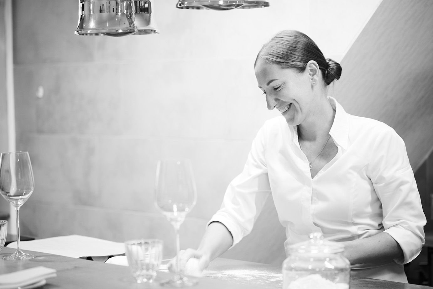 Photo en noir et blanc de la cheffe Slava Tcherbak finalisant une assiette en souriant au restaurant Fleur de Sel