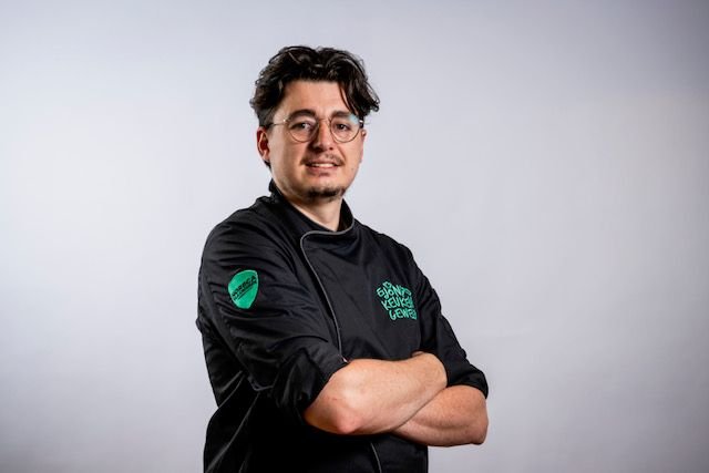 Photo couleur du chef Hendrik Dequeker en veste de cuisine noire, les bras croisés