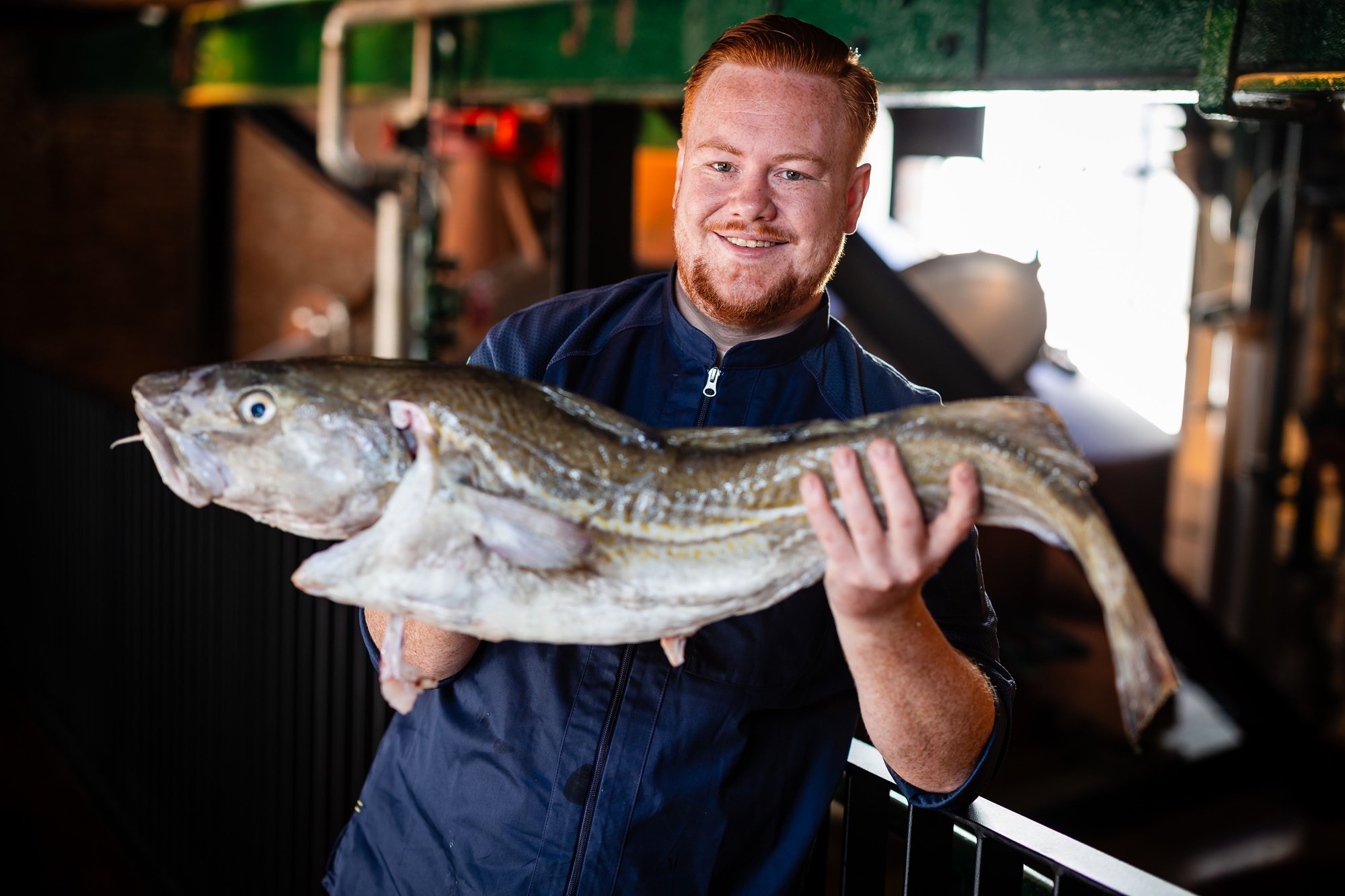 Photo couleur du chef Bram Simons montrant fièrement un poisson frais au restaurant Emiel
