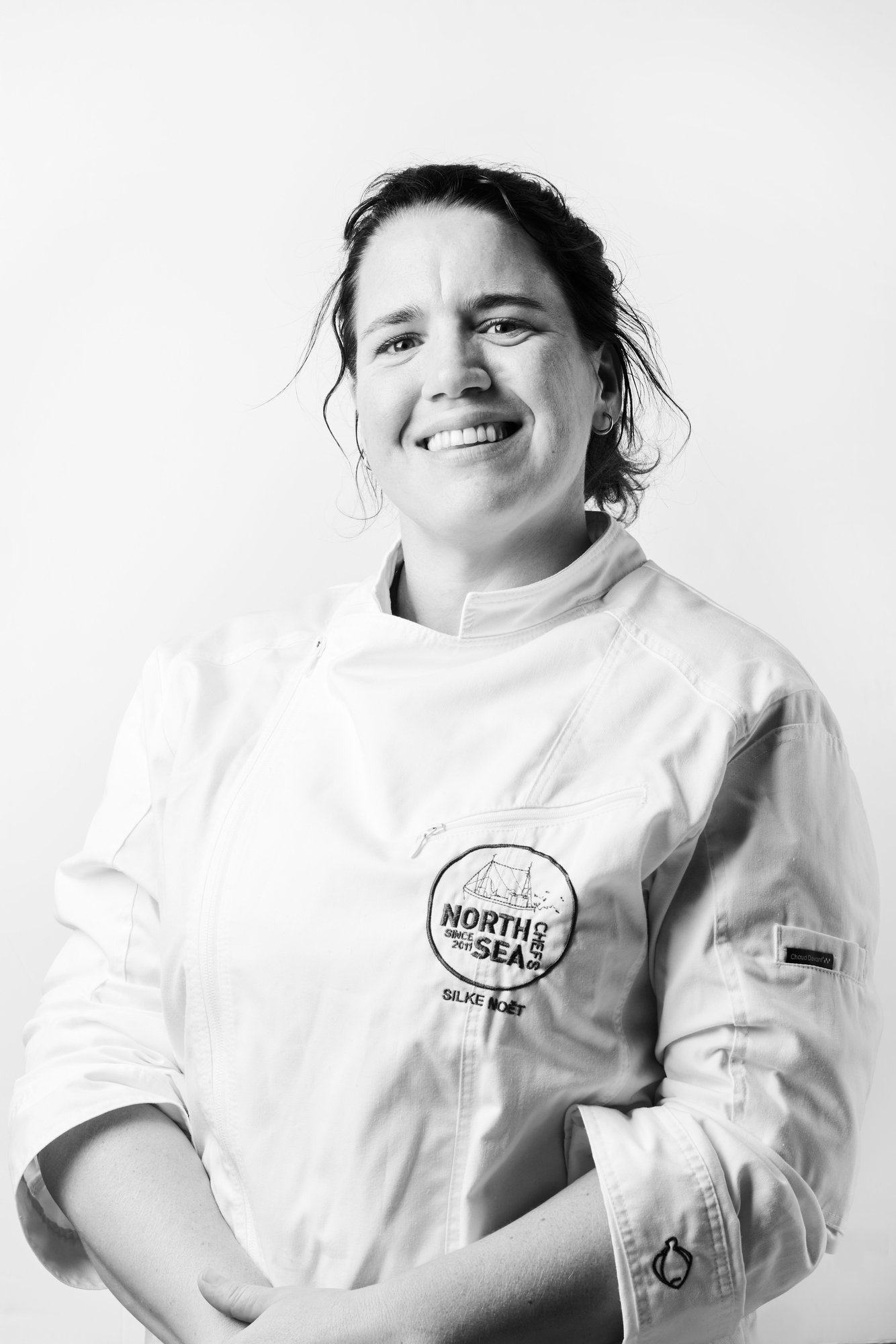 Portrait en noir et blanc de la cheffe Silke Noët en veste de cuisine blanche NorthSeaChefs