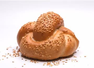 Close-up of a freshly baked bread roll topped with sesame seeds on a white background.