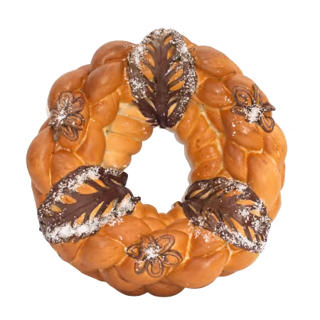 Braided bread wreath decorated with chocolate and powdered sugar designs.