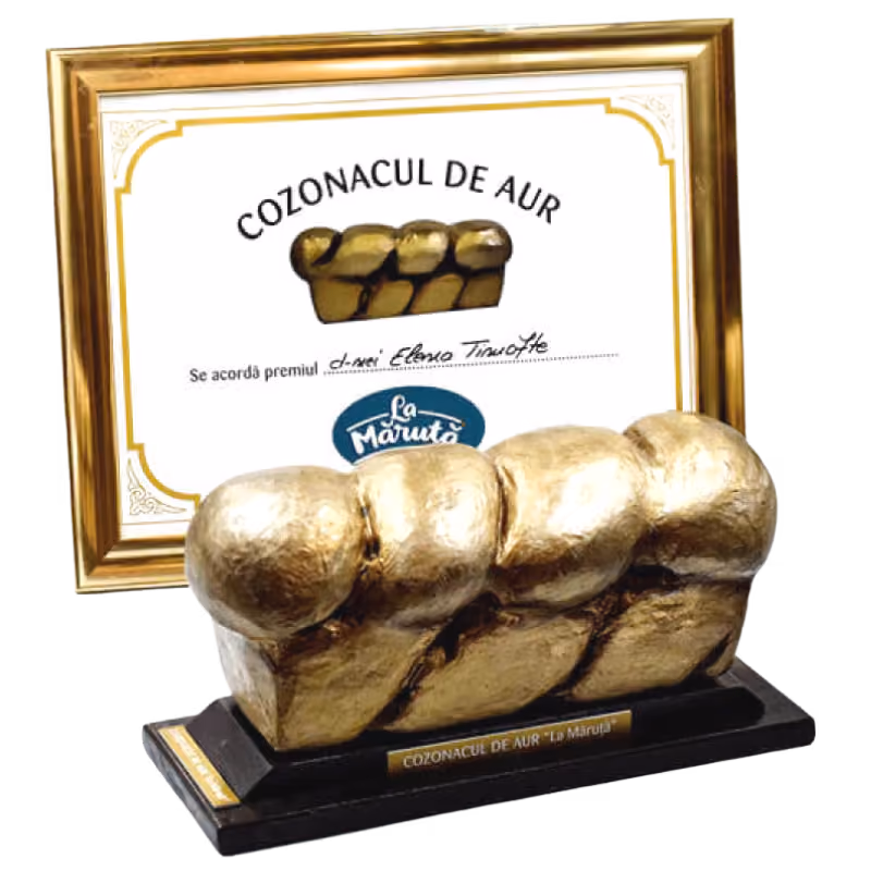 Golden trophy shaped like a braided loaf of cozonac with a framed certificate in the background reading 'COZONACUL DE AUR' and the La Măruță logo.