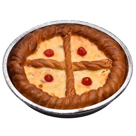 Round baked pie with a braided crust and four red cherries arranged in quadrants on a cheese topping inside a foil pan.