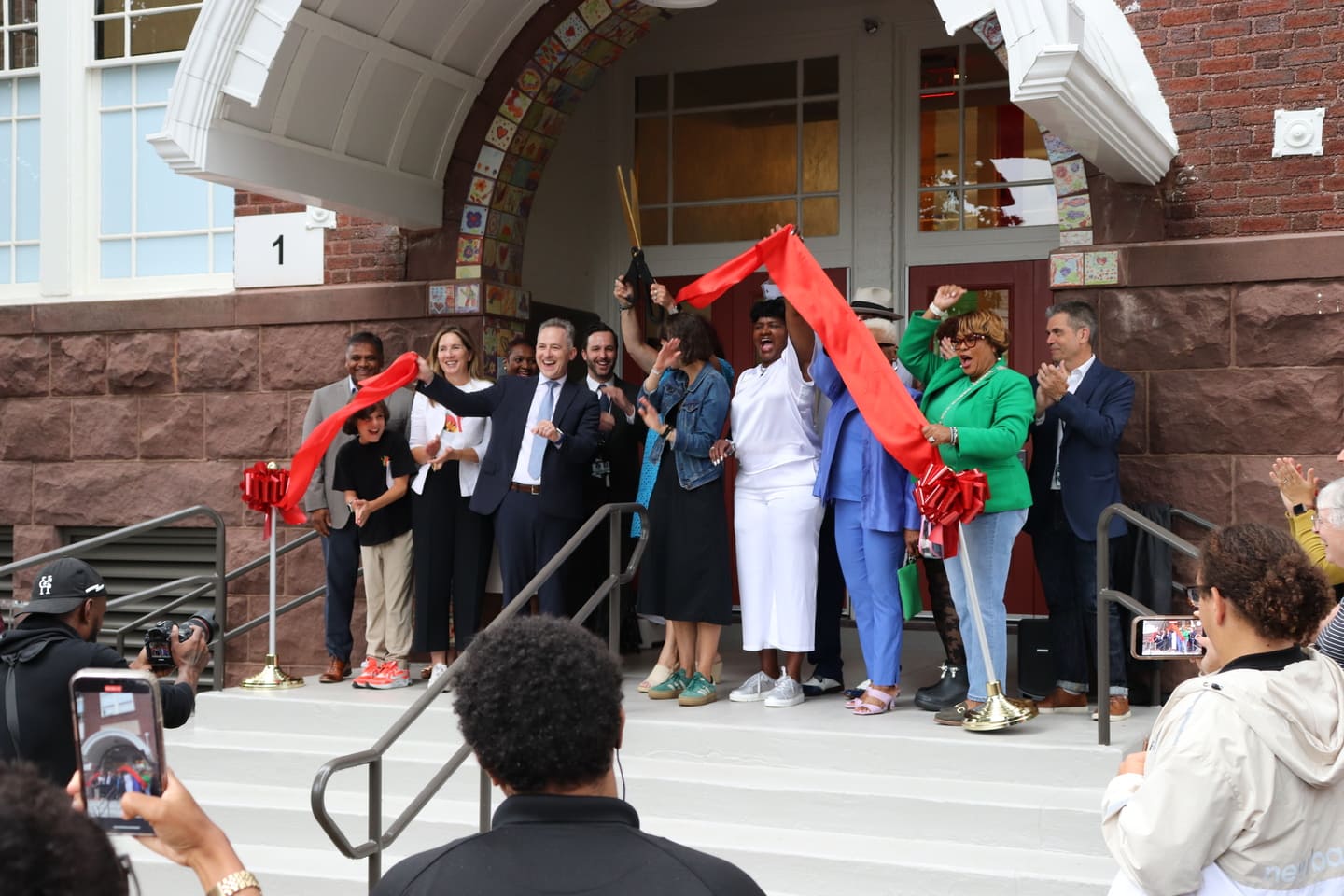 A ribbon cutting ceremony at the entry to a historic building.
