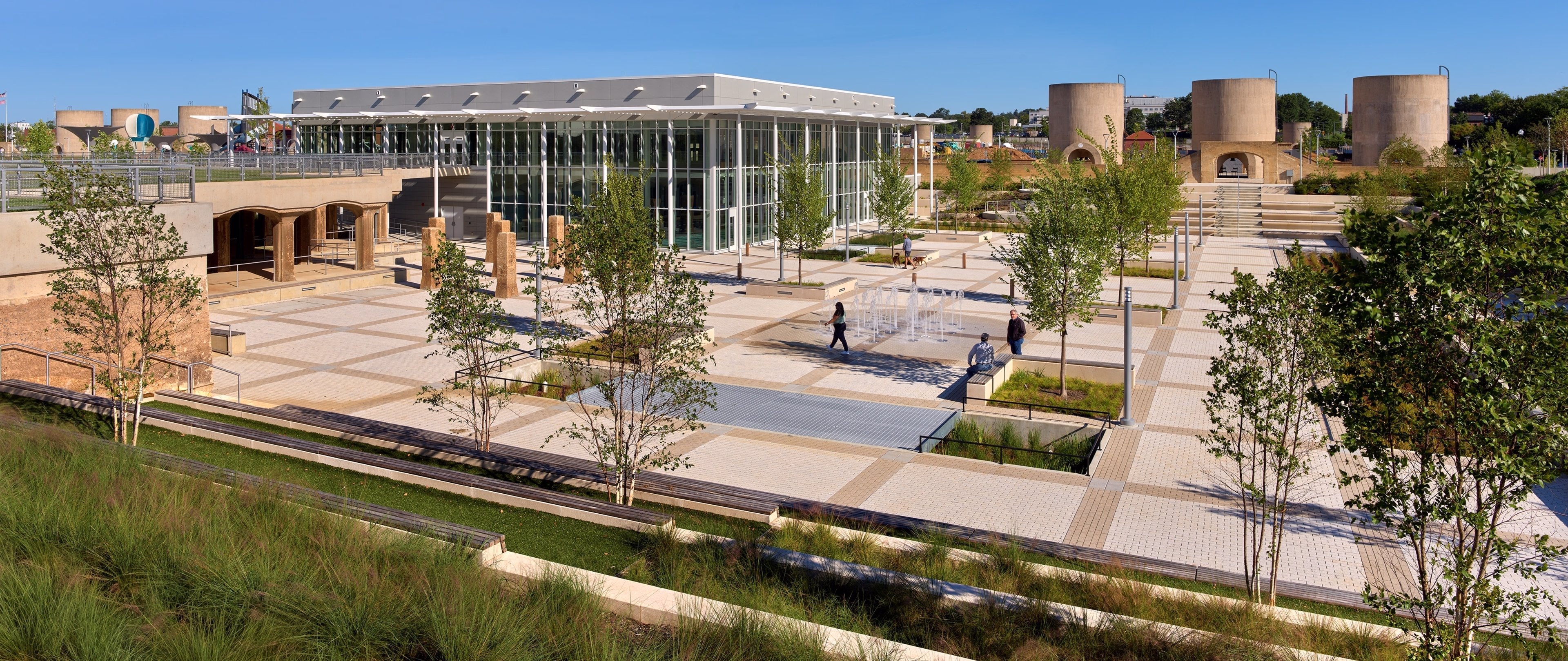 Wide shot of the new recreation center and the plaza with splash pads. Preserved silos are seen in the distance.