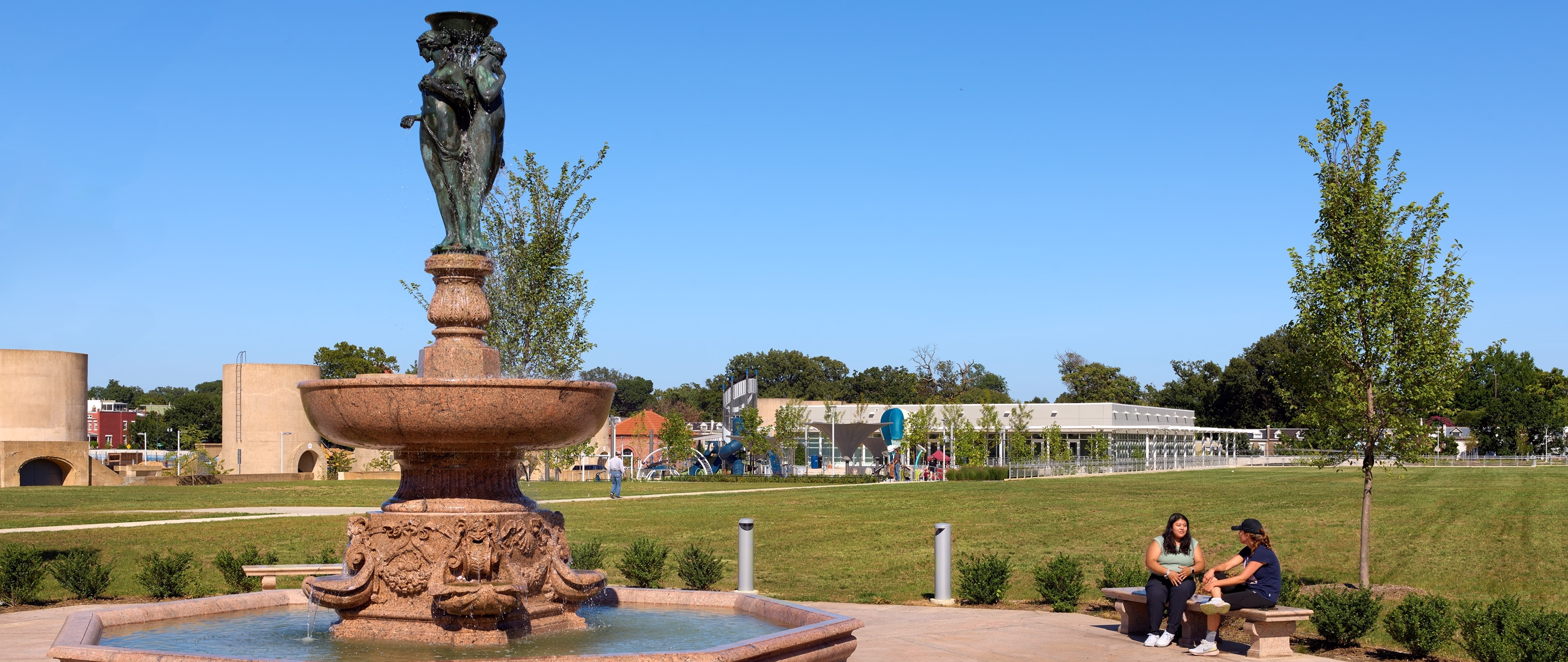 Visitors sit on a bench near the fountain.