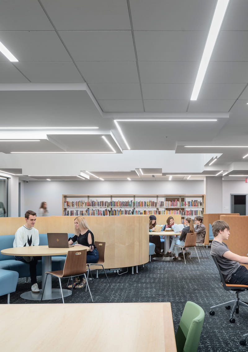 A photo of teens working from a laptop at a round table with a partial wall divider.