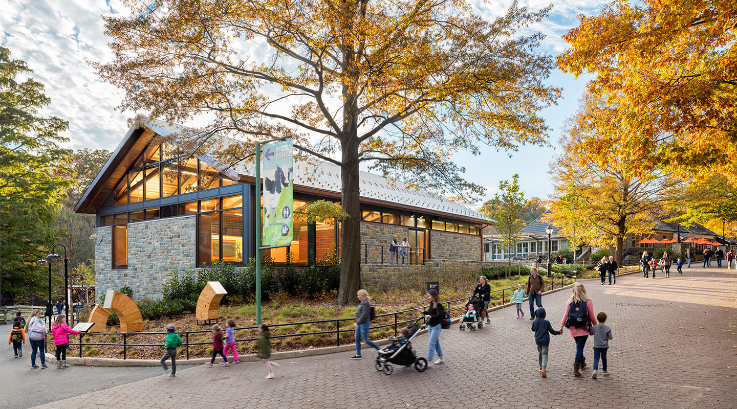 A photo of visitors walking past a stone building.