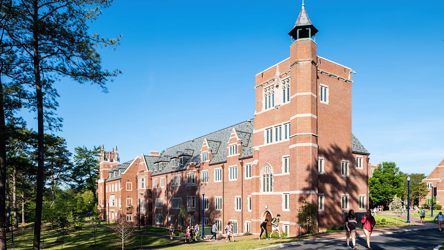 A photo of a brick building with students walking around it.