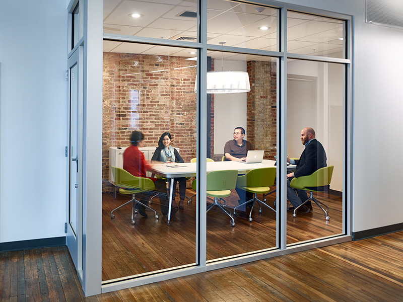 A photo of a small group of people in a glass conference room.