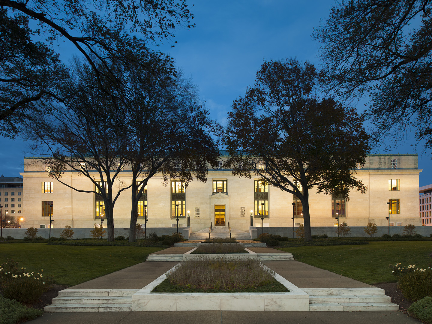 A photo of the exterior of the National Academy of Sciences in Washington, DC at night time.