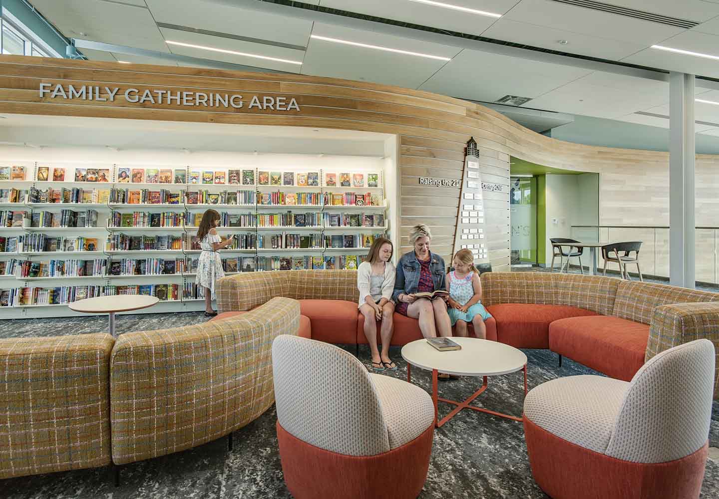 A photo of a mother reading with two daughters in the warm-toned, cozy family gathering area.