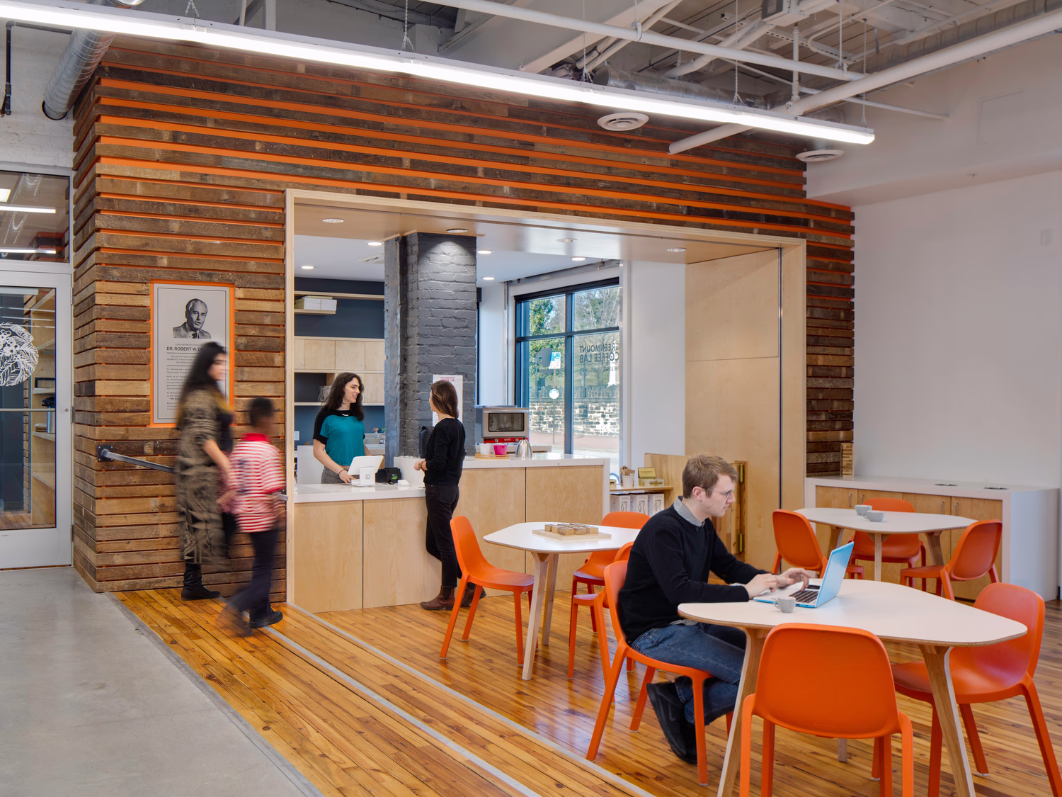 Visitors interact at a cafe, which features reused wood in the paneling.