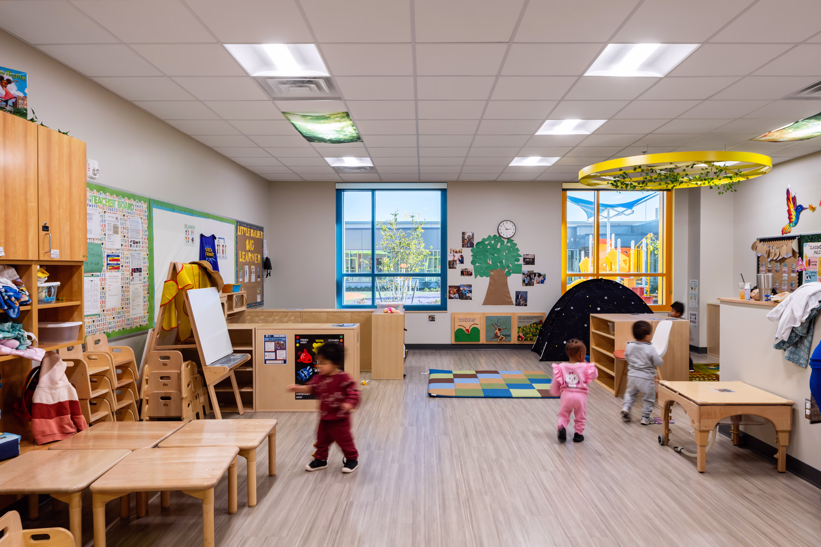 A preschool classroom with windows overlooking a playground.