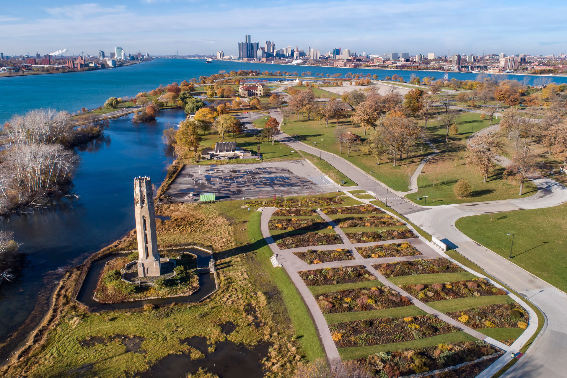 A photo of an urban park with a river and downtown skyline in the background.