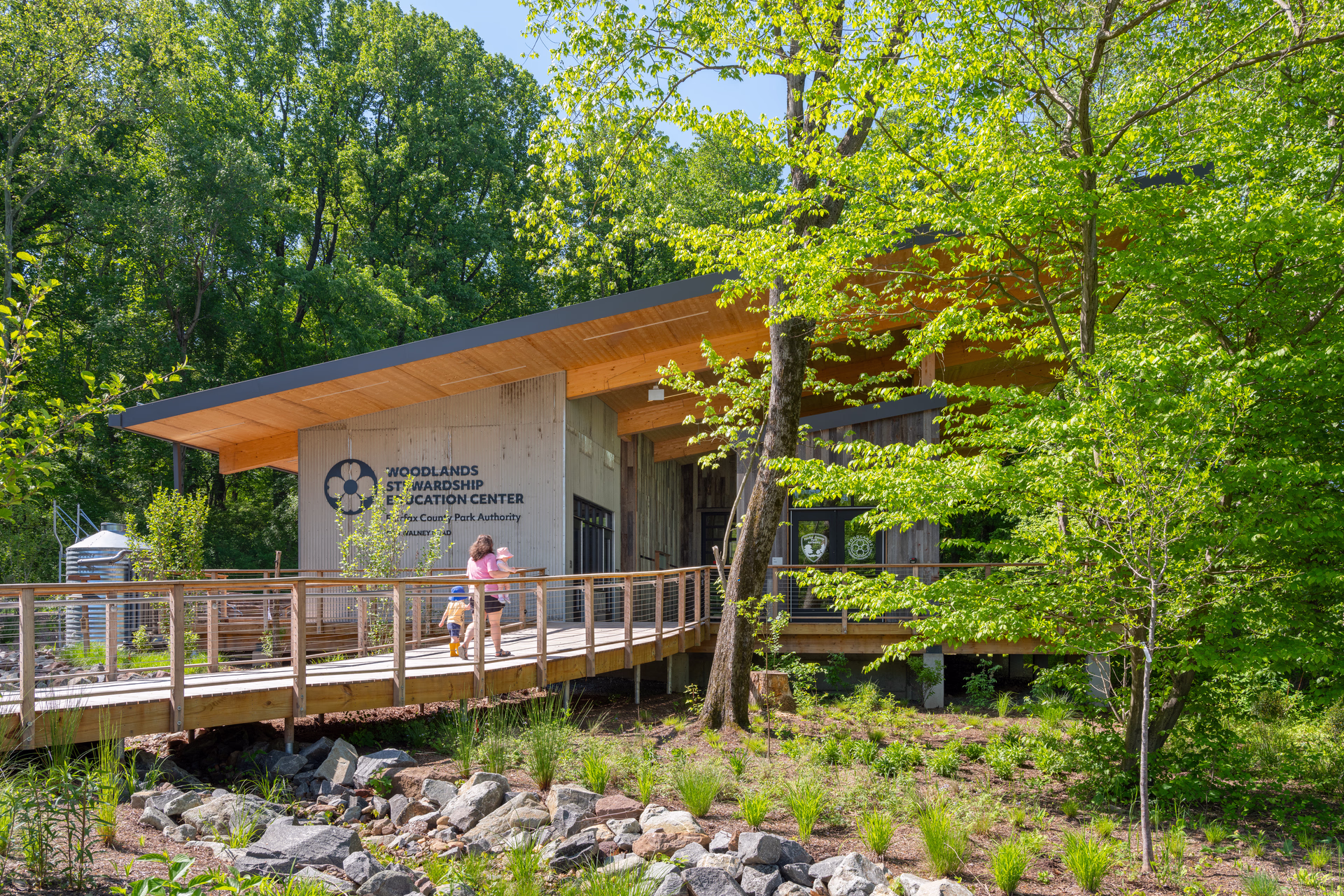 A photo of a family walking toward a sloped-roof building surrounded by trees.