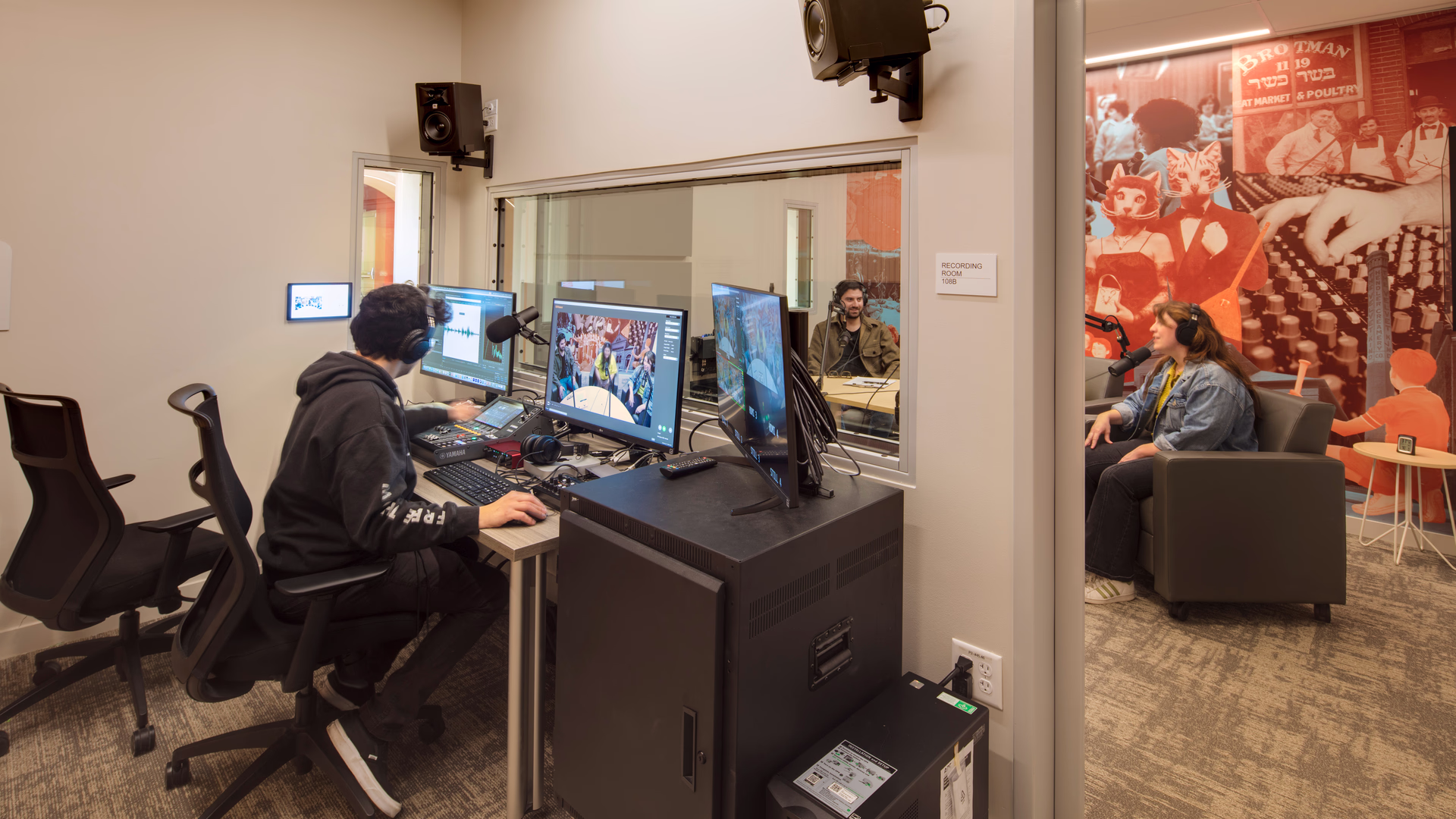 An interior photo of a production booth and adjacent recording studio.