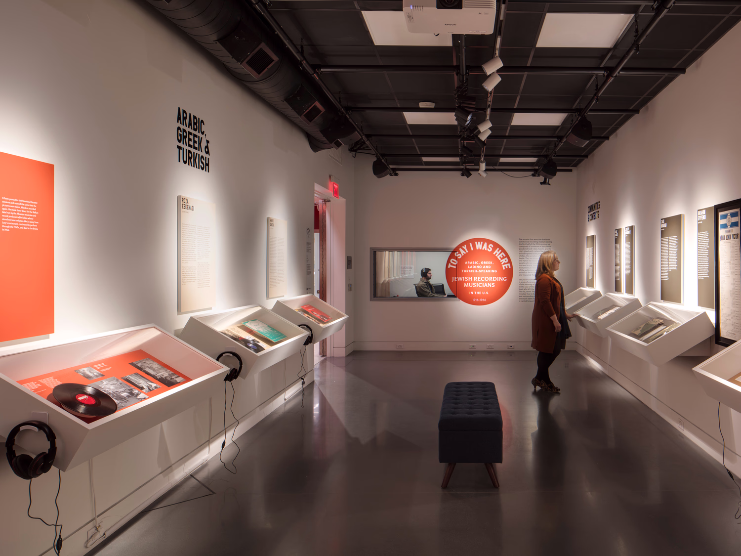 An interior photo of a multimedia gallery with a window into an adjacent production studio.