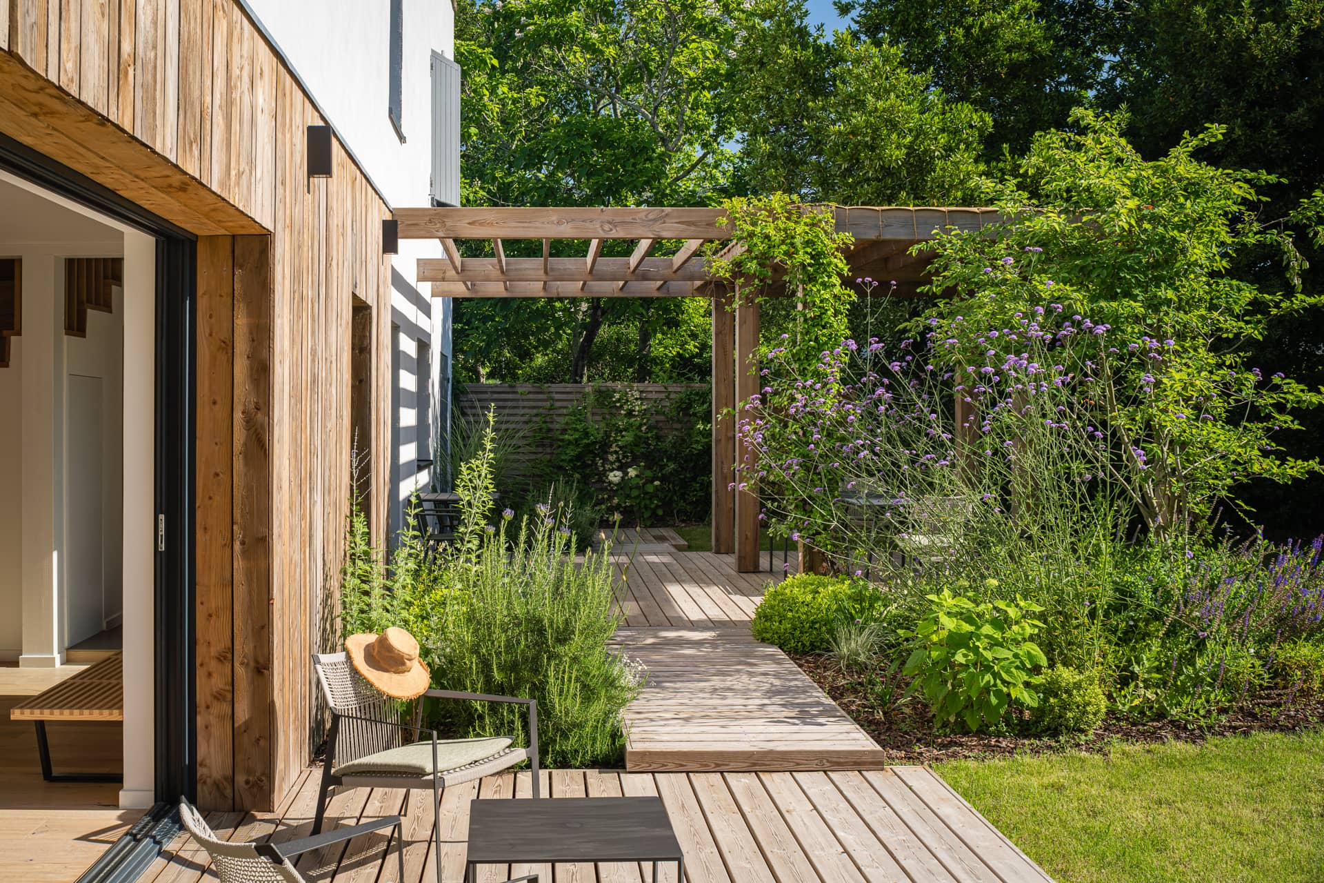 Terrasse en bois avec pergola végétalisée, mobilier extérieur et jardin