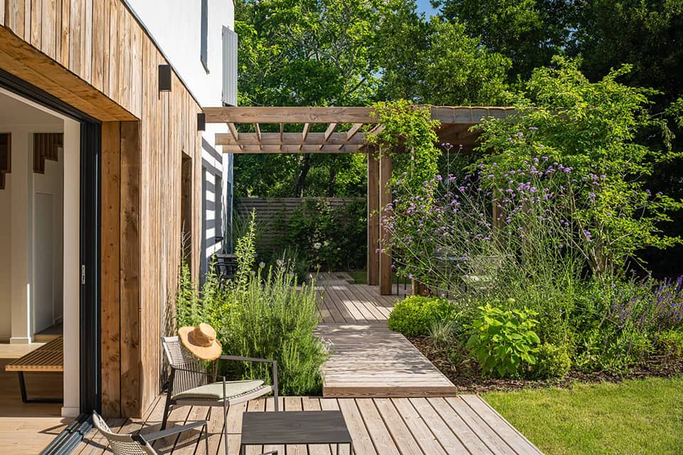 Terrasse en bois avec pergola végétalisée, mobilier extérieur et jardin