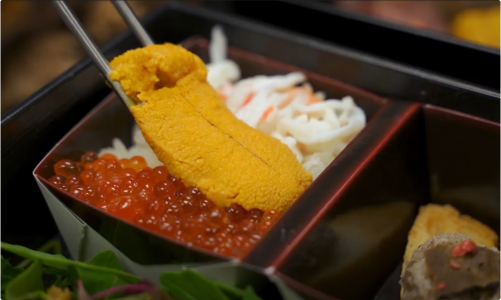 Chopsticks lift up a fresh piece of uni at Kawabe