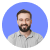 Smiling man with beard wearing a light blue shirt against white background.