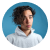 Headshot of a young man with curly hair wearing a white shirt against a white background.