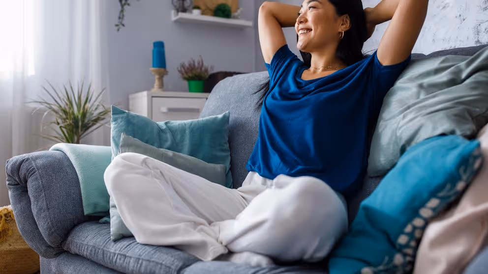 A woman sitting back and relaxing on comfy furniture.