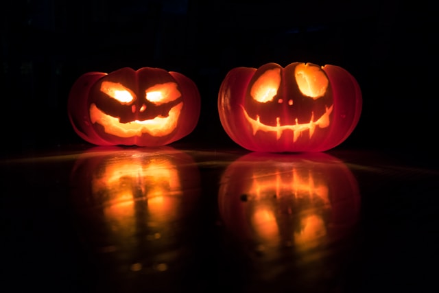 Banner for event. Lit jack-o-lantern pumpkins in the dark.