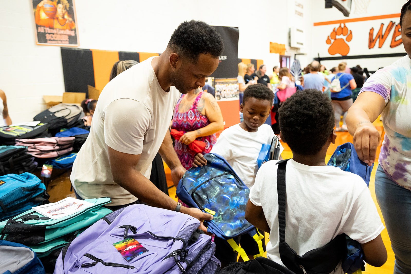 Will Allen handing a new backpack to a student