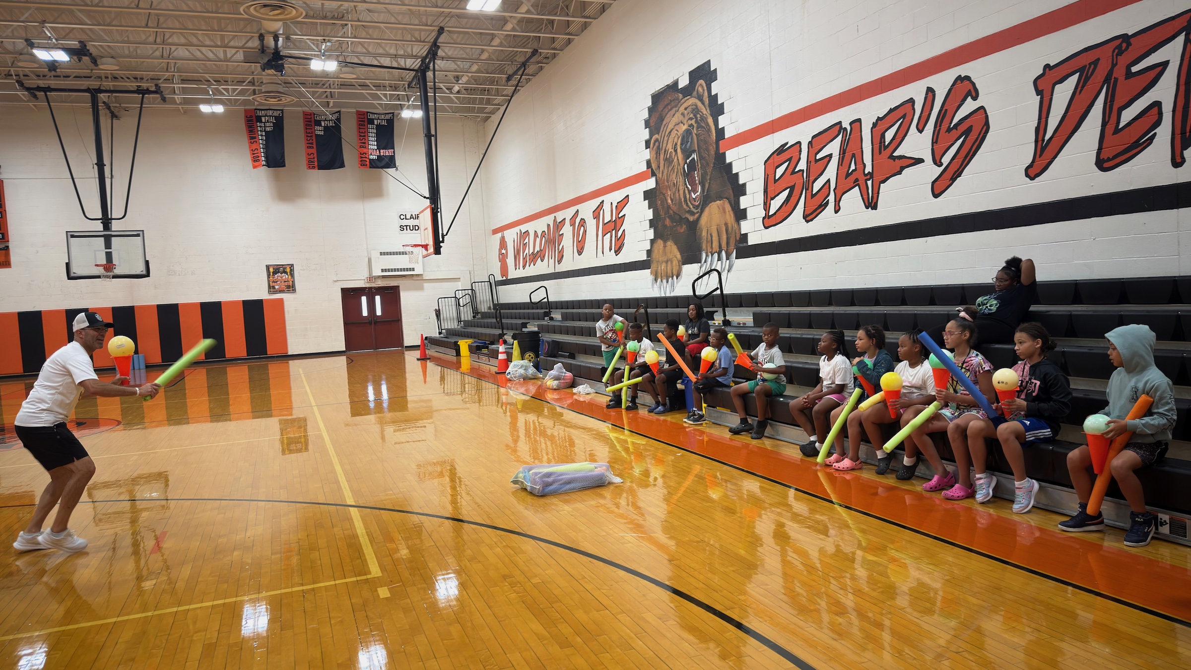 Coach Dave Gray speaking to the students in a gym