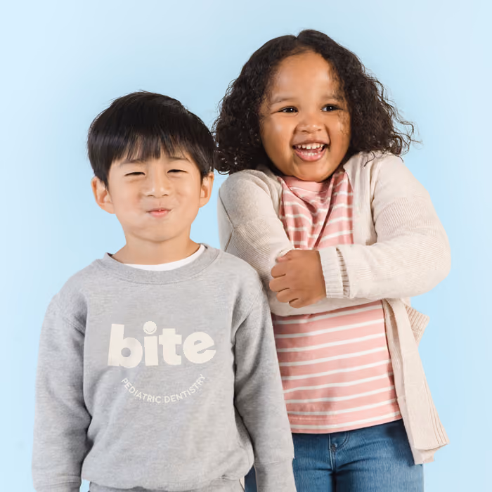 Happy children smiling and wearing Bite Pediatric Dentistry branded merchandise, showcasing our fun and friendly dental office environment