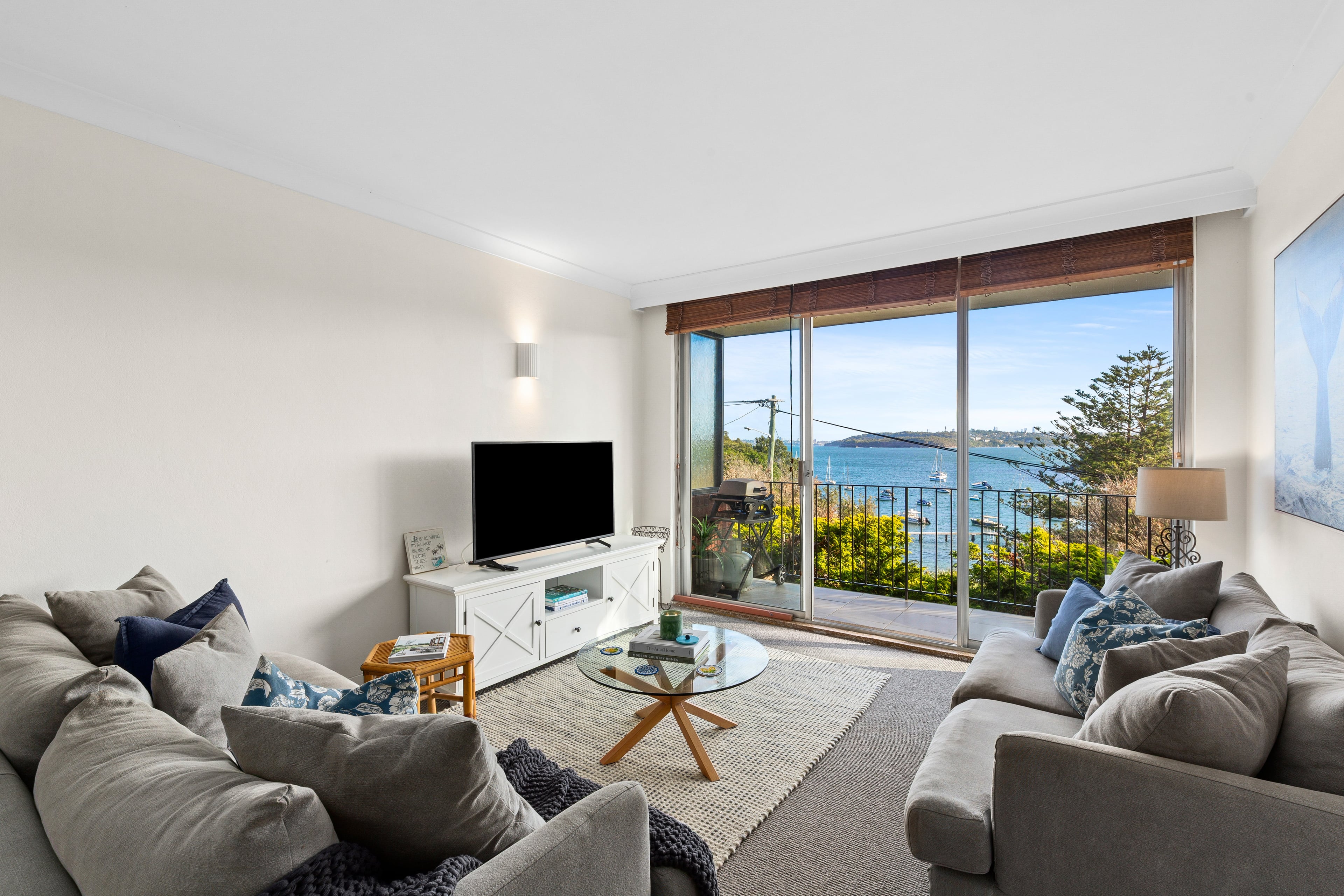 Unwind in a light-filled living area where plush seating, a large-screen TV, and sweeping harbour views set the tone for slow mornings and sunset evenings by the water.