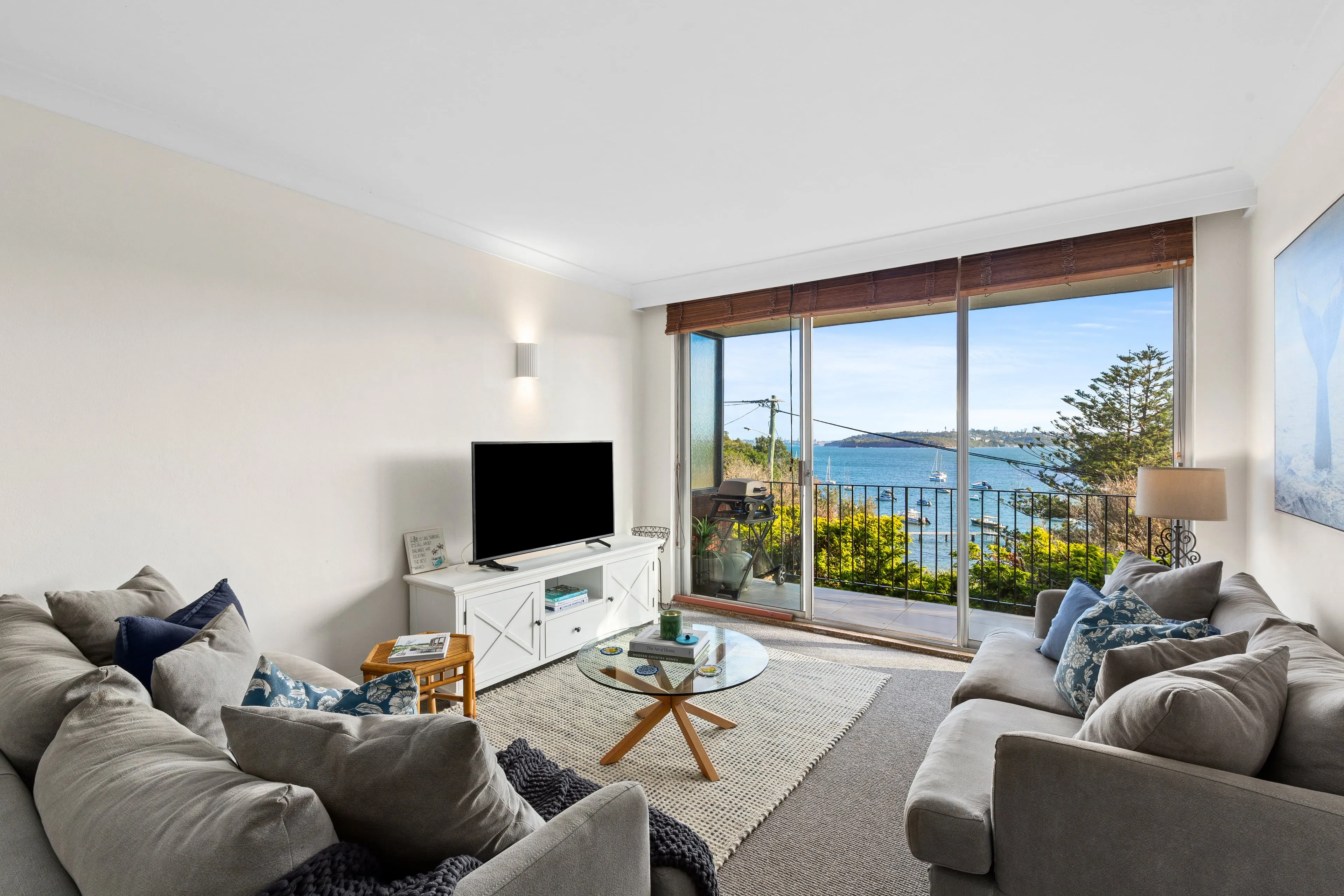 Unwind in a light-filled living area where plush seating, a large-screen TV, and sweeping harbour views set the tone for slow mornings and sunset evenings by the water.
