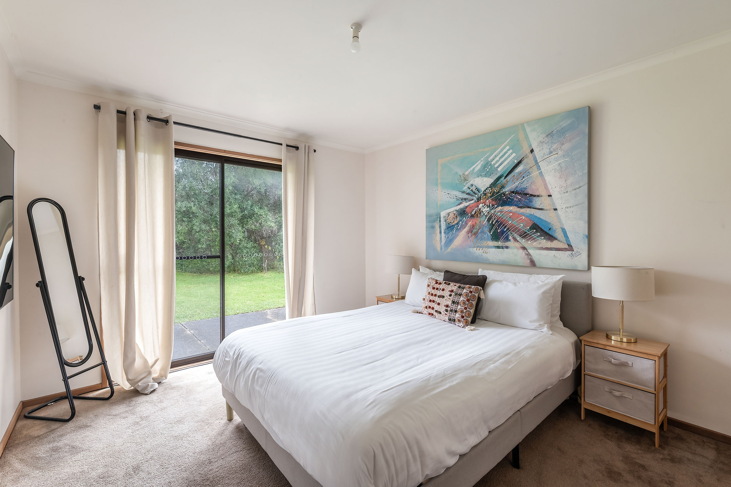 Wake to garden views from the primary bedroom, where a queen bed and calming palette create a restful retreat after a day of coastal exploring.