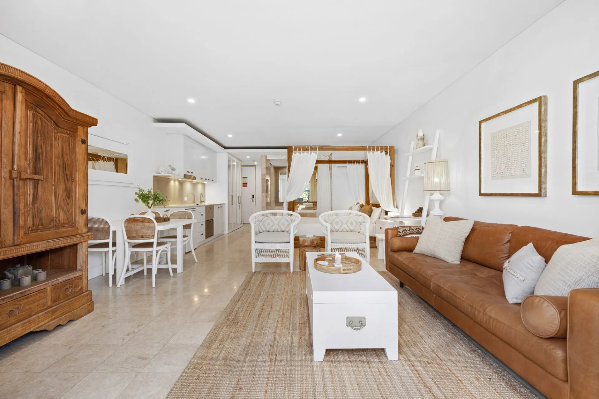 Tan leather couch, jute rug and a carved timber cabinet, chosen by a local interior designer rather than a standard furniture package