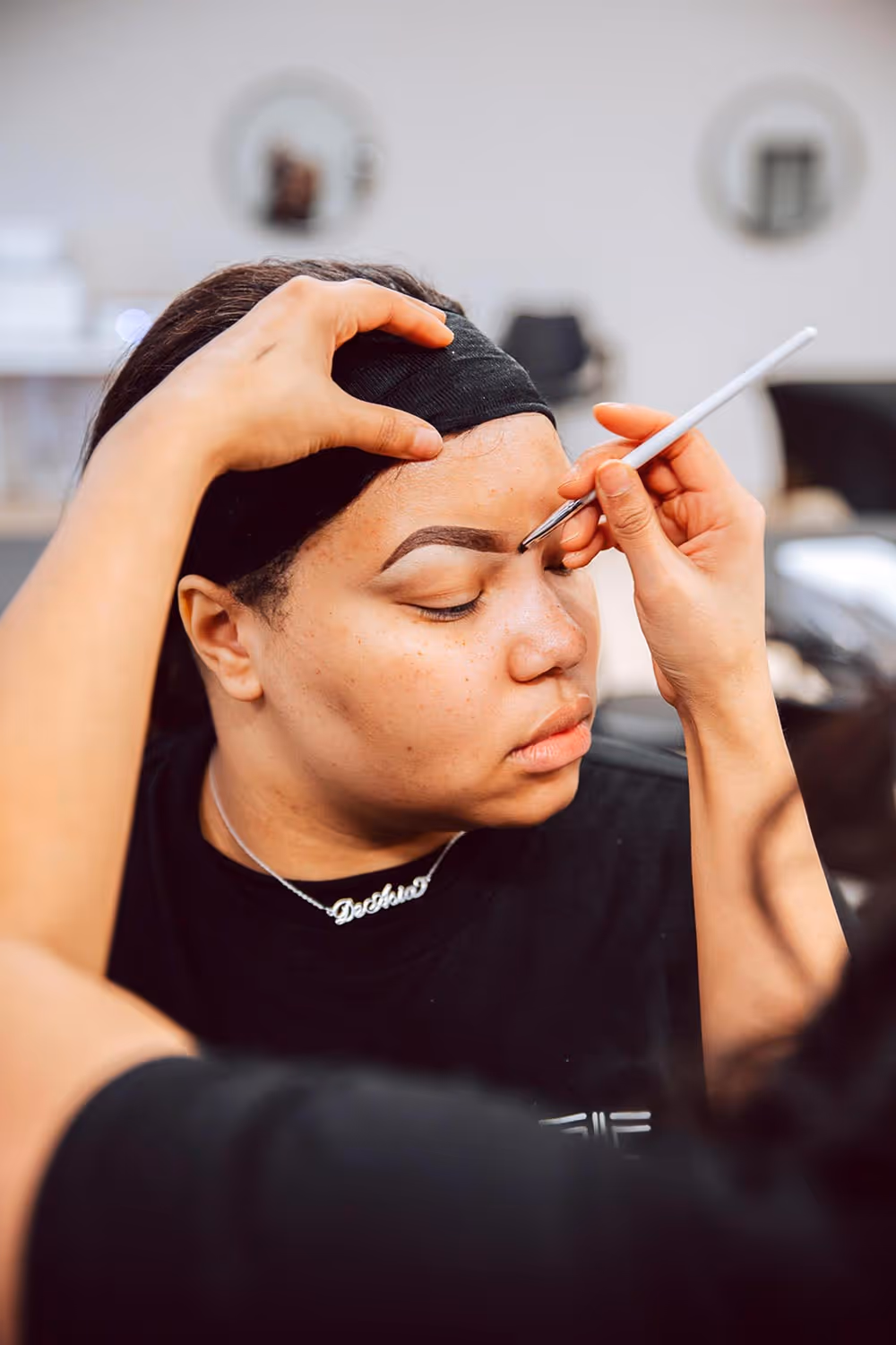 Aesthetics student shaping client's brows