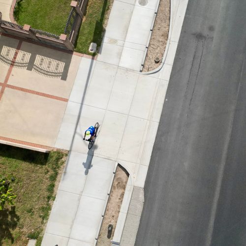 A cyclist rides down a sidewalk-level bike path.
