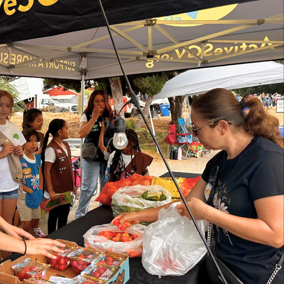 A group of children and families gather at the ActiveSGV booth as fresh produce is handed out.