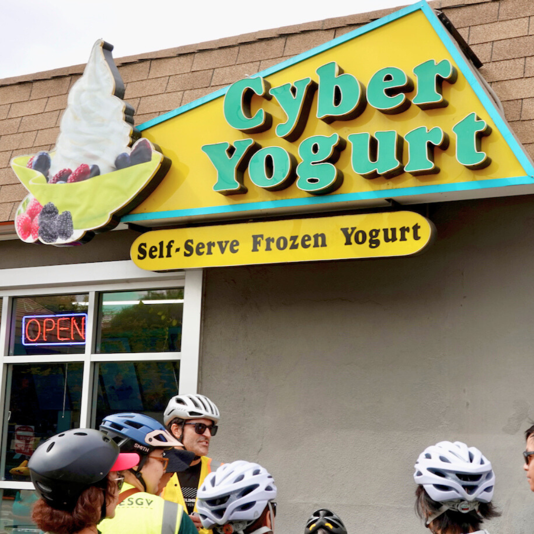 A group of cyclists in helmets gather outside Cyber Yogurt, a frozen yogurt shop in South El Monte.