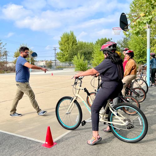 An instructor teaches cyclists with helmets to bike.