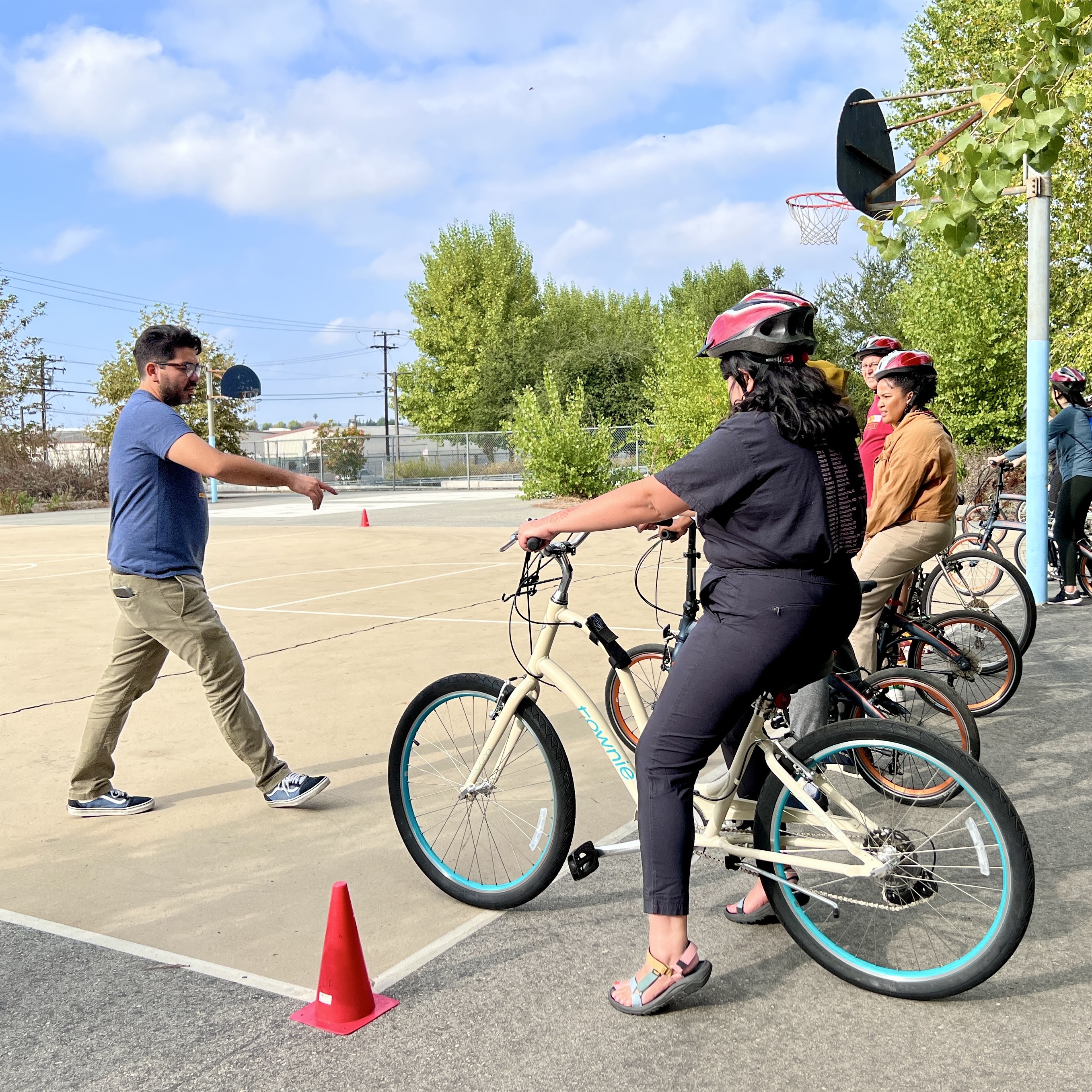 An instructor teaches cyclists with helmets to bike. 