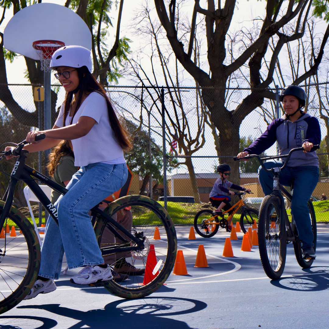 Two girls riding on an obstacle course. Orange cones direct the path. 
