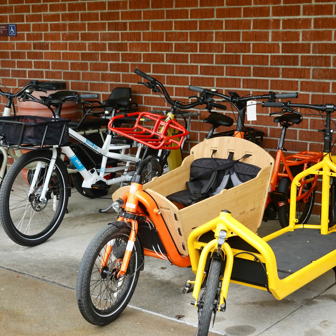 Three electric cargo bikes lined against a brick wall