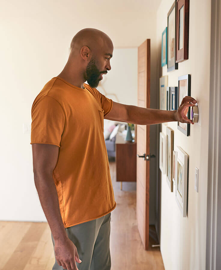 A man adjusting his thermostat