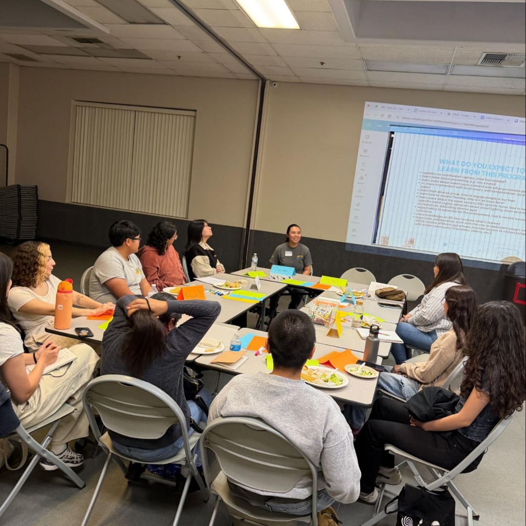 Community Leadership Program participants sit around tables during a workshop, discussing environmental issues and reviewing presentation materials.