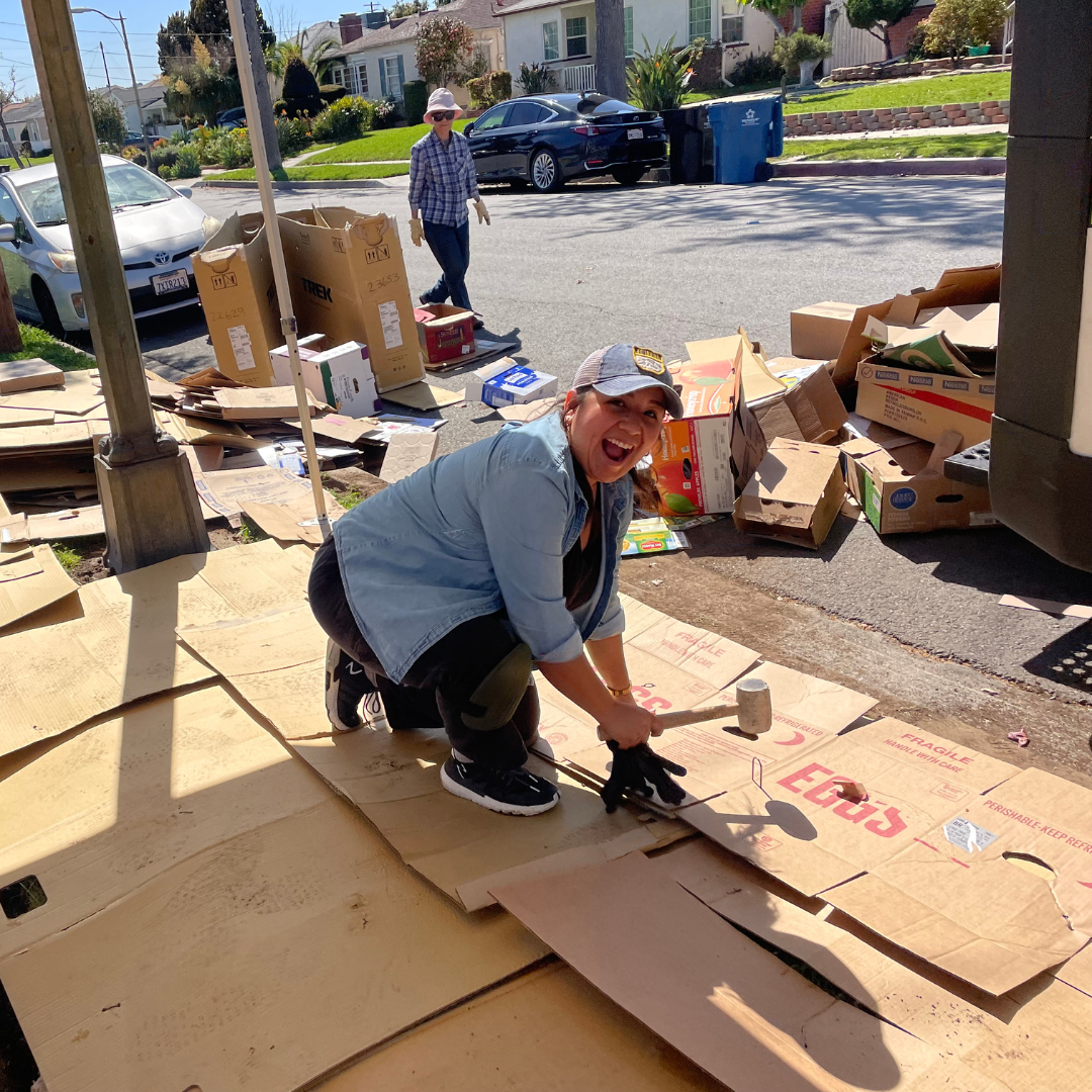 Volunteer prepares cardboard sheet mulch that will be used during a rain garden installation.