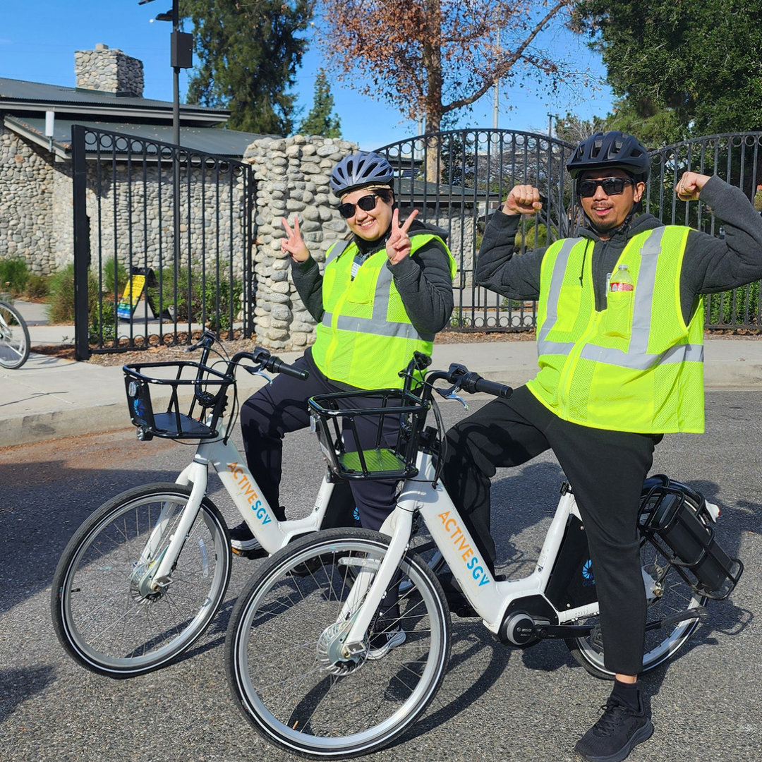 Two riders pose with e-bikes and safety vests before heading out on the trail.