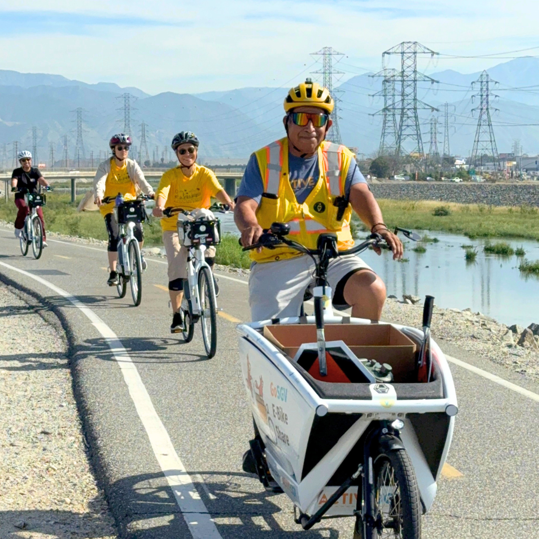 ActiveSGV staff on a cargo e-bike guiding participants along a river trail.